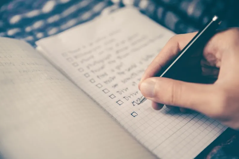 Checkliste und Stift auf Schreibtisch neben Laptop